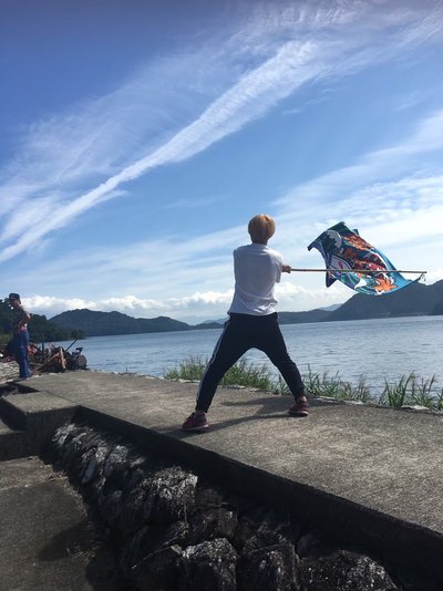 沖島で旗をふる学生