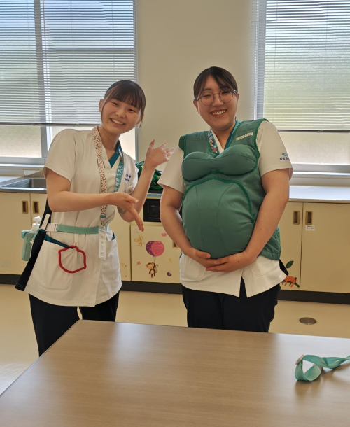 妊婦体験コーナーを案内する学生.png
