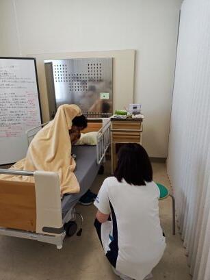 耳をおさえて苦しそうな統合失調症患者を演じる俳優にかかわる学生.jpg