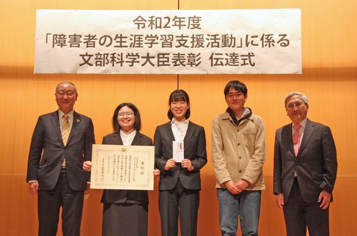 ボランティアサークルHarmonyの代表者と廣川理事長、倉茂理事との「障害者の生涯学習支援活動」に係る文部科学大臣表彰を受けた記念写真
