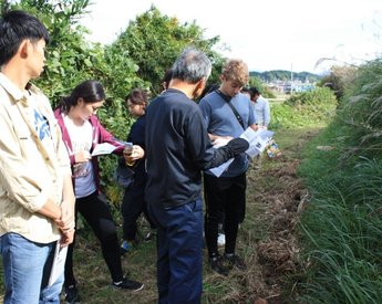 留学生複数人と地域の方が資料片手に散策