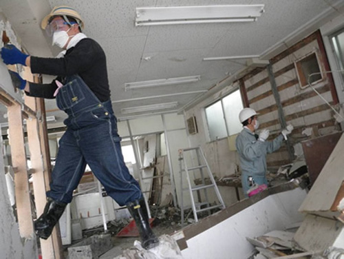 浸水家屋の壁面取り壊し作業をする玉井さん(左)